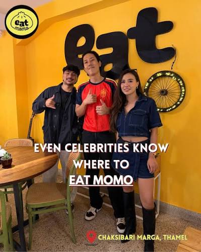 Three guests in front of the yellow eat momo wall at the Thamel branch
